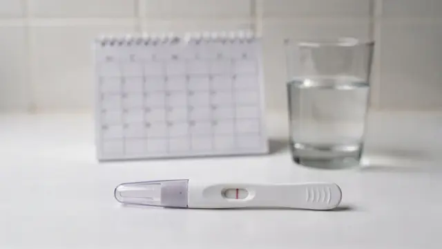 Schwangerschaftstest auf dem Badewannenrand mit Kalender zum Thema frühester Schwangerschaftstest vor der Periode