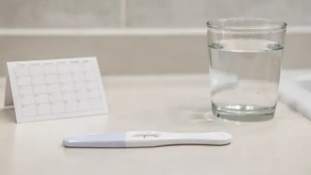 Schwangerschaftstest, Kalender und Glas Wasser als Frühtest-Motiv zum Thema Schwangerschaftstest