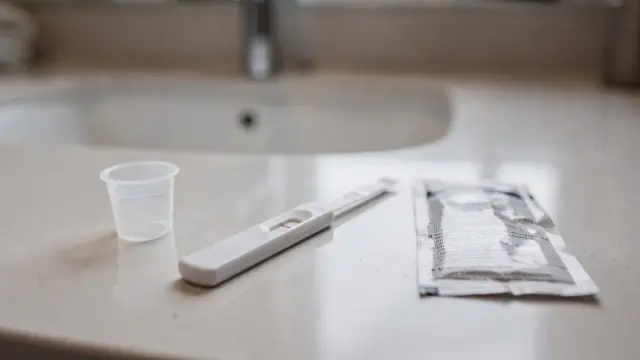 Schwangerschaftstest-Streifentest mit Teststreifen, Probenbecher und Anleitung im Badezimmer