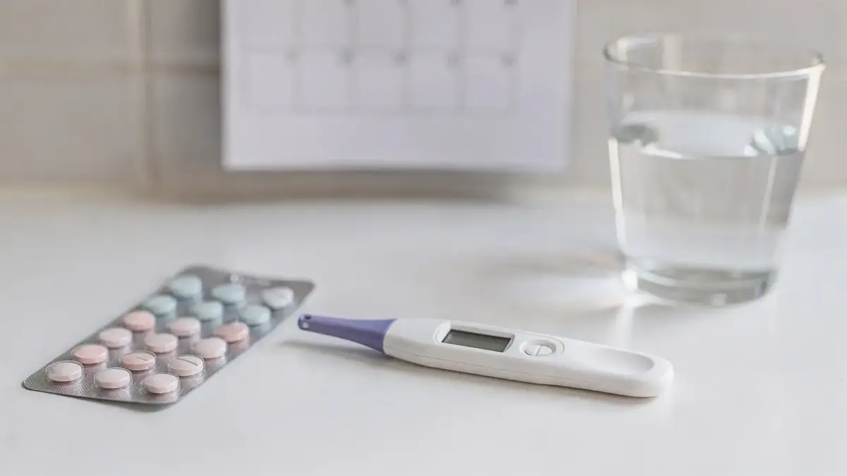 Digitaler Schwangerschaftstest im Badezimmer neben Kalender und Pille zum Thema Test nach der Pille