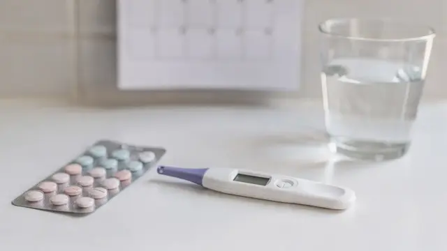 Digitaler Schwangerschaftstest im Badezimmer neben Kalender und Pille zum Thema Test nach der Pille