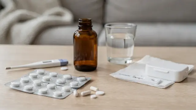 Medikamente nach positivem Test: Pillendose, Blister und Smartphone in einer Beratungsszene